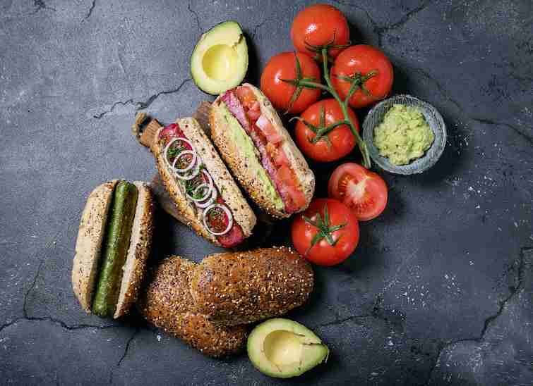 Vegeterian dog food served with tomatoes, avacado, onion and buns.